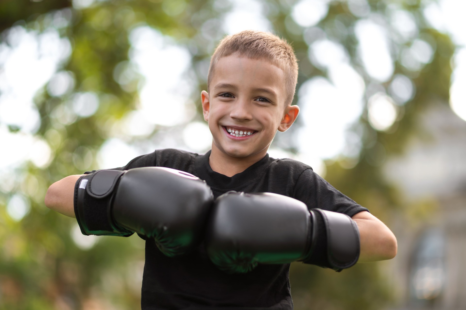 Little kickboxer in gloves looking happy and smiling